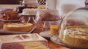 Variedad de postres expuestos sobre una mesa de madera, incluyendo pasteles y dulces en vitrinas.