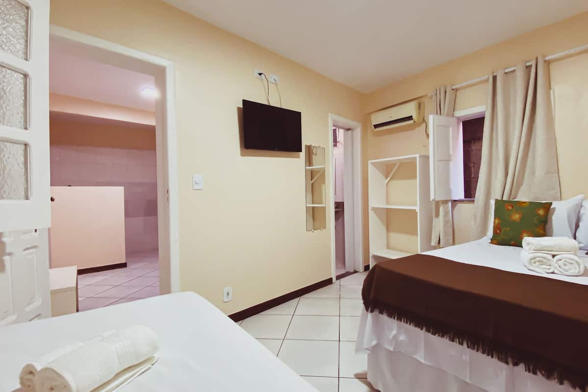Ein Hotelzimmer mit Bett, Fernseher, Kleiderschrank und einem durchgegangenen Tür sichtbar werdendem Badezimmer.