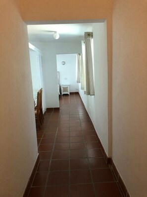 A narrow hallway with tiled flooring, white walls, and a white door at the end.