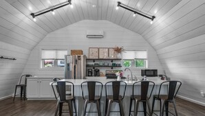Una cocina moderna con una isla central, taburetes de bar y un comedor.