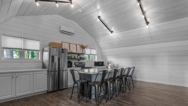 Una cocina moderna con techo curvo, electrodomésticos integrados y una isla central con taburetes de bar.