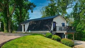 Una casa moderna con una amplia instalación de paneles solares, un porche cubierto y un césped bien cuidado.