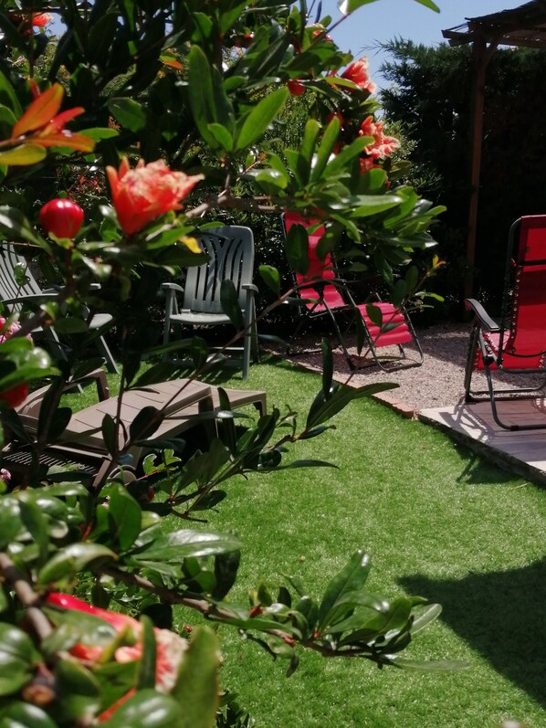 A garden with artificial grass, green and red chairs, and various plants. - 2-room, garden-level, small, charming house with a 3-star rating (Fréjus)