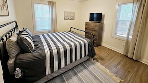 A bedroom with a bed, a dresser, a ceiling fan, and a television. - Madrona's Guesthouse- Spacious 2BR with Huge Fenced Yard (North Charleston)