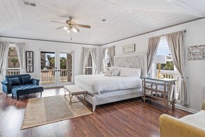A bedroom with a bed, a bench, a chair, a bedside table, and a ceiling fan.