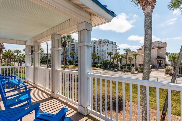 A covered outdoor area with white railings and blue chairs.