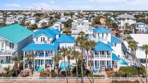 A coastal residential area with multiple houses, some with blue roofs, and a clear view of the ocean in the background.