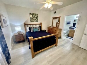 Une chambre à coucher avec un lit en bois, une table de chevet, une commode et un miroir.