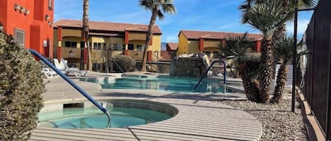 A resort with multiple swimming pools, palm trees, and a red building.