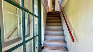 Una escalera con barandilla de madera y una puerta con paneles de vidrio.
