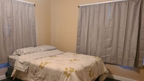 A bedroom with a bed, curtains, and a wooden floor. - Brightly Homely House  (Odem)