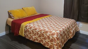 A bed with a patterned bedspread, a red and yellow blanket, and two pillows. - Brightly Homely House  (Odem)