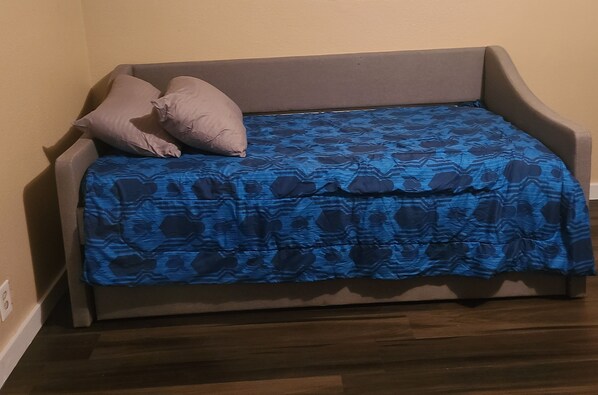 Un canapé gris recouvert d’un tissu à motifs bleus, avec deux coussins.