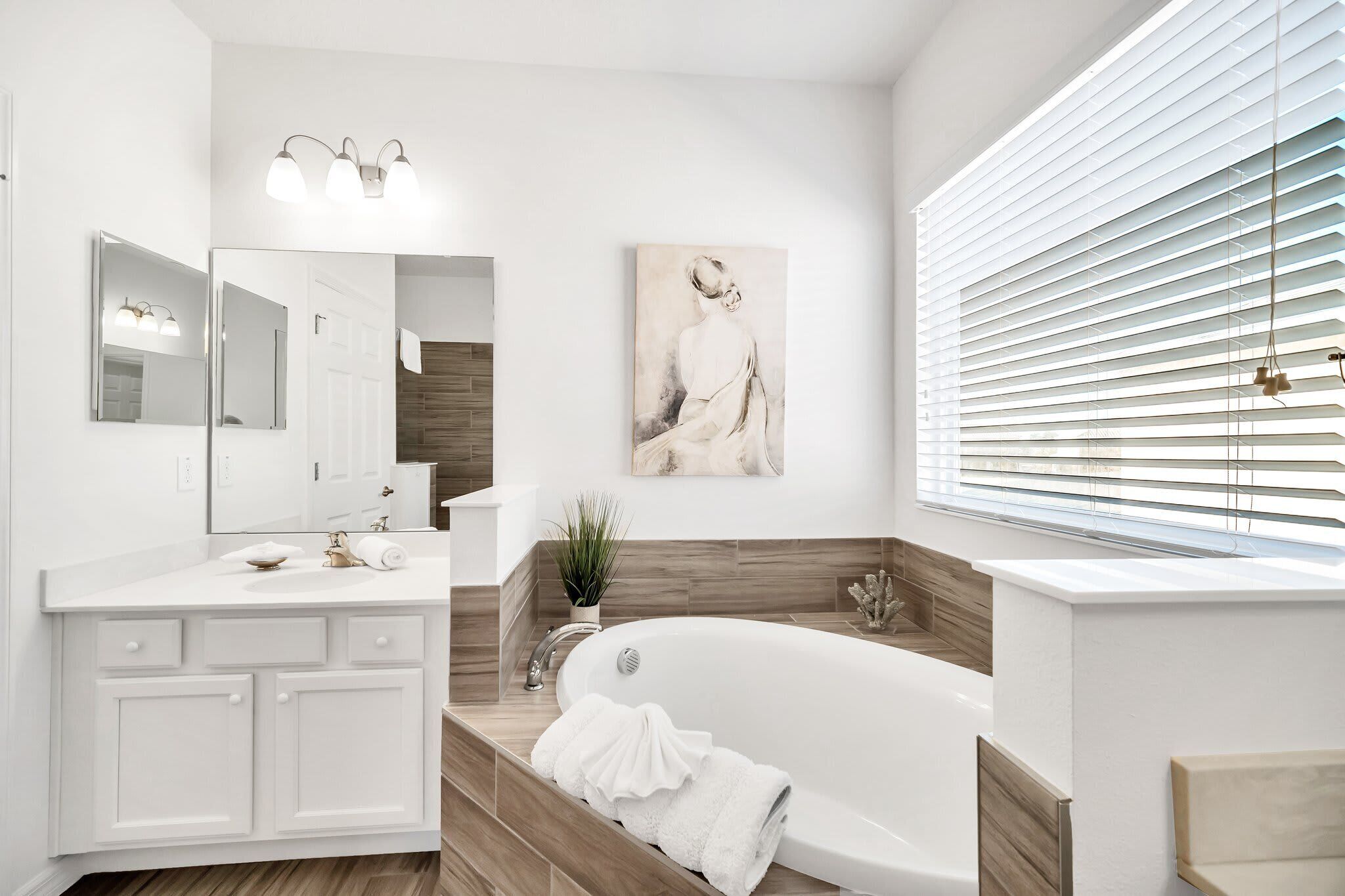 A modern bathroom with a freestanding bathtub, a large mirror, and a wall-mounted light fixture.