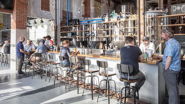 A bar area with stools and a counter, surrounded by industrial-style decor and brewing equipment.