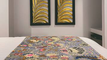 Una habitación con una cama, dos cuadros en la pared y una colcha estampada.