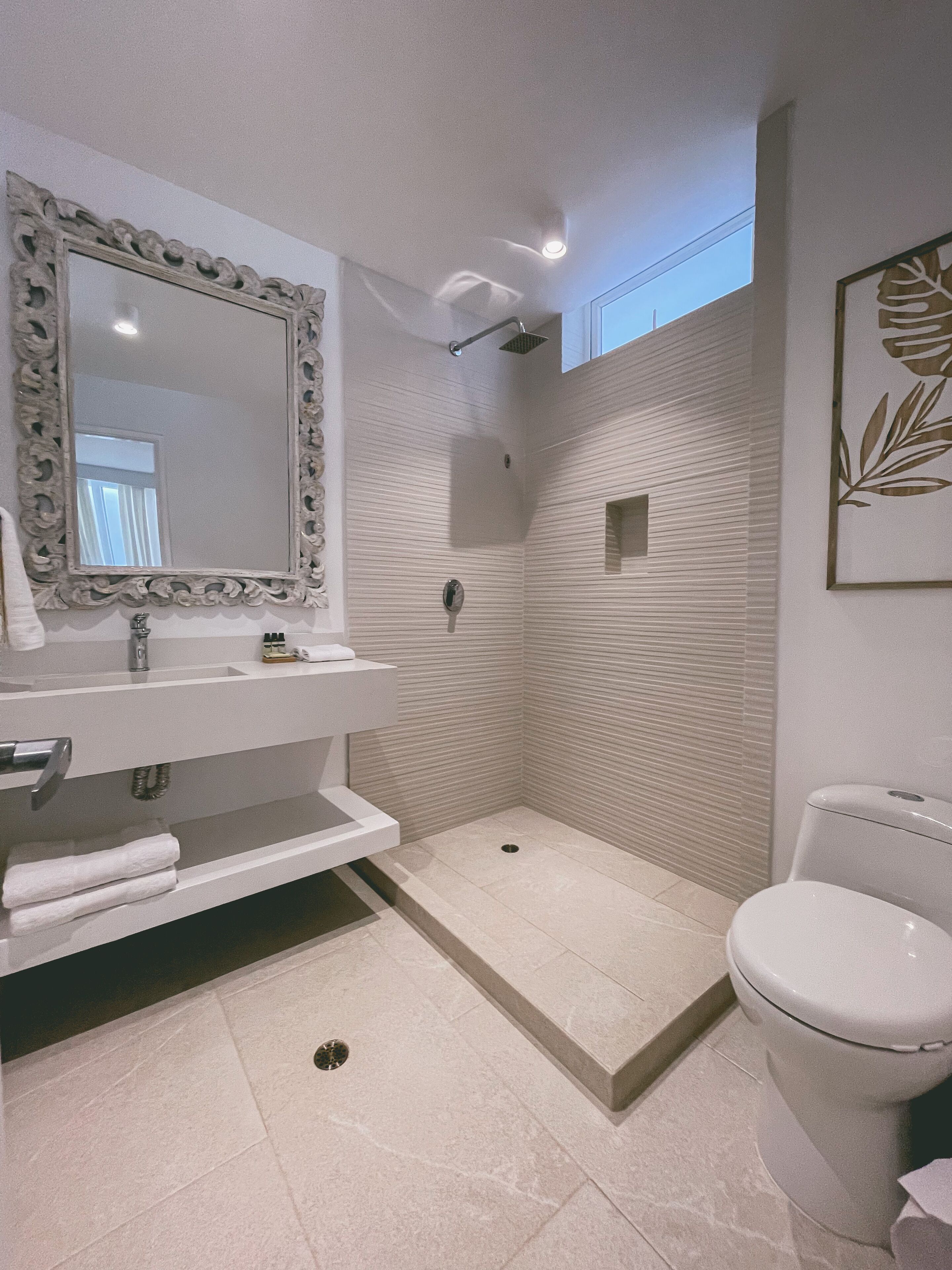 Un baño moderno con un espejo grande, lavamanos blanco y un inodoro.