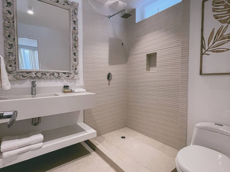 Un baño moderno con un espejo grande, lavamanos blanco y un inodoro.