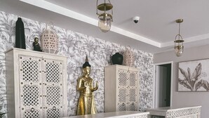 A room with a patterned floor, a central console table with intricate carvings, and a Buddha statue.