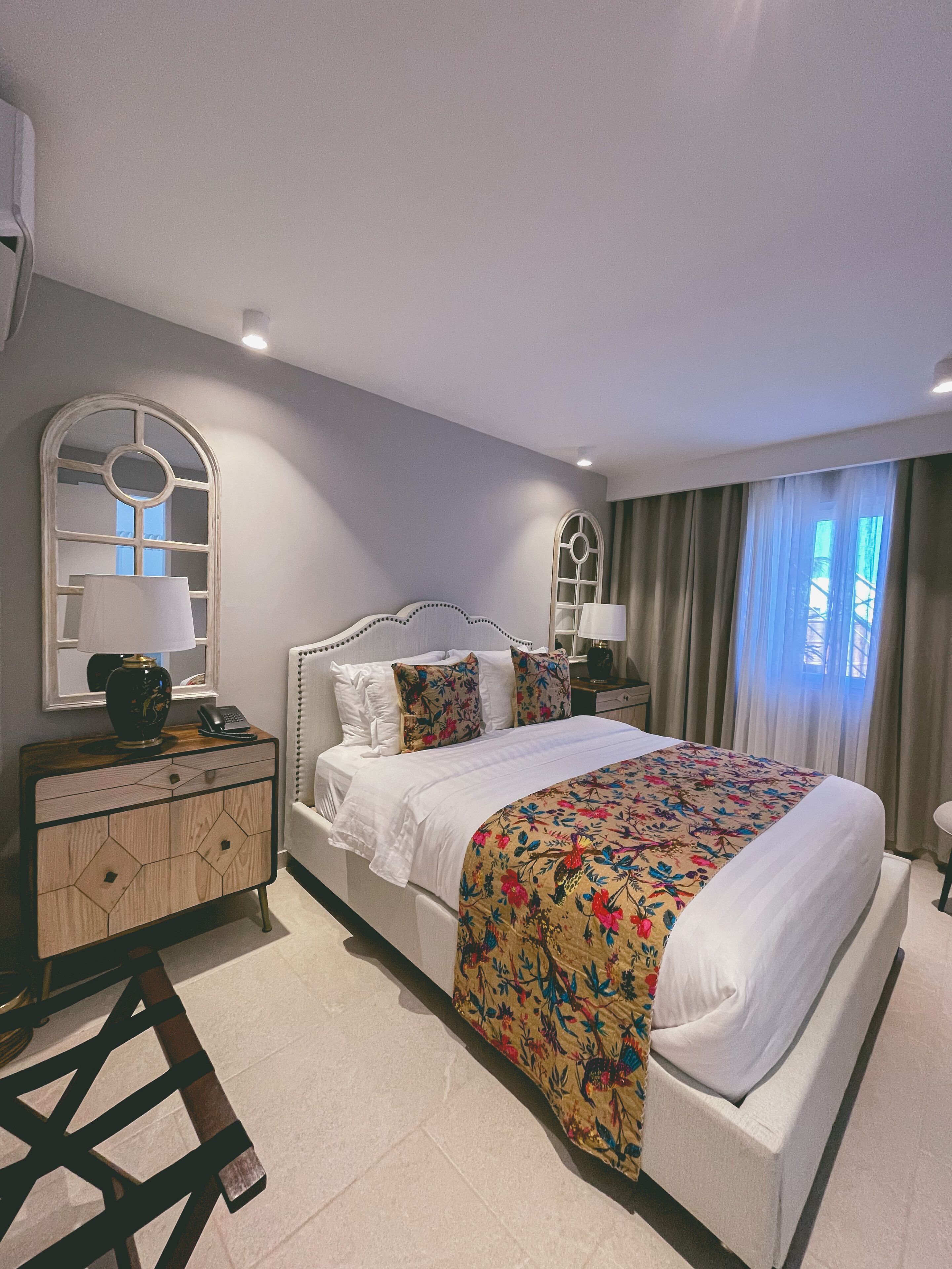 Une chambre à coucher avec un lit, une table de chevet, une commode et un miroir.