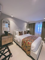 A bedroom with a bed, a nightstand, a dresser, and a mirror.