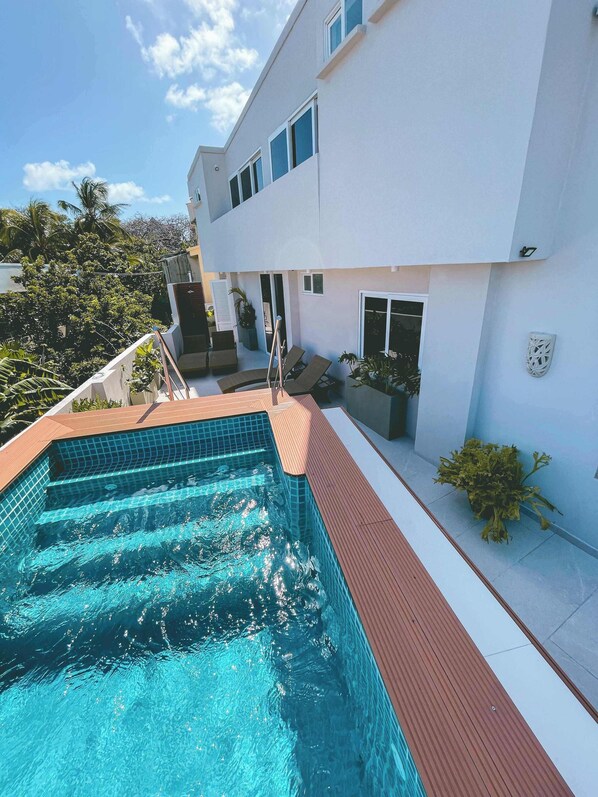 A modern building with a swimming pool, outdoor seating, and potted plants. - Hotel Boutique Casa Hendaus - Adults Only (San Andrés)