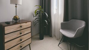 A modern living room with a wooden dresser, a lamp, a chair, and a potted plant.