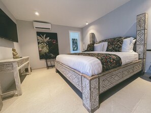 A bedroom with a large bed, a bedside table, an air conditioning unit, and a wall-mounted TV. - Hotel Boutique Casa Hendaus - Adults Only (San Andrés)
