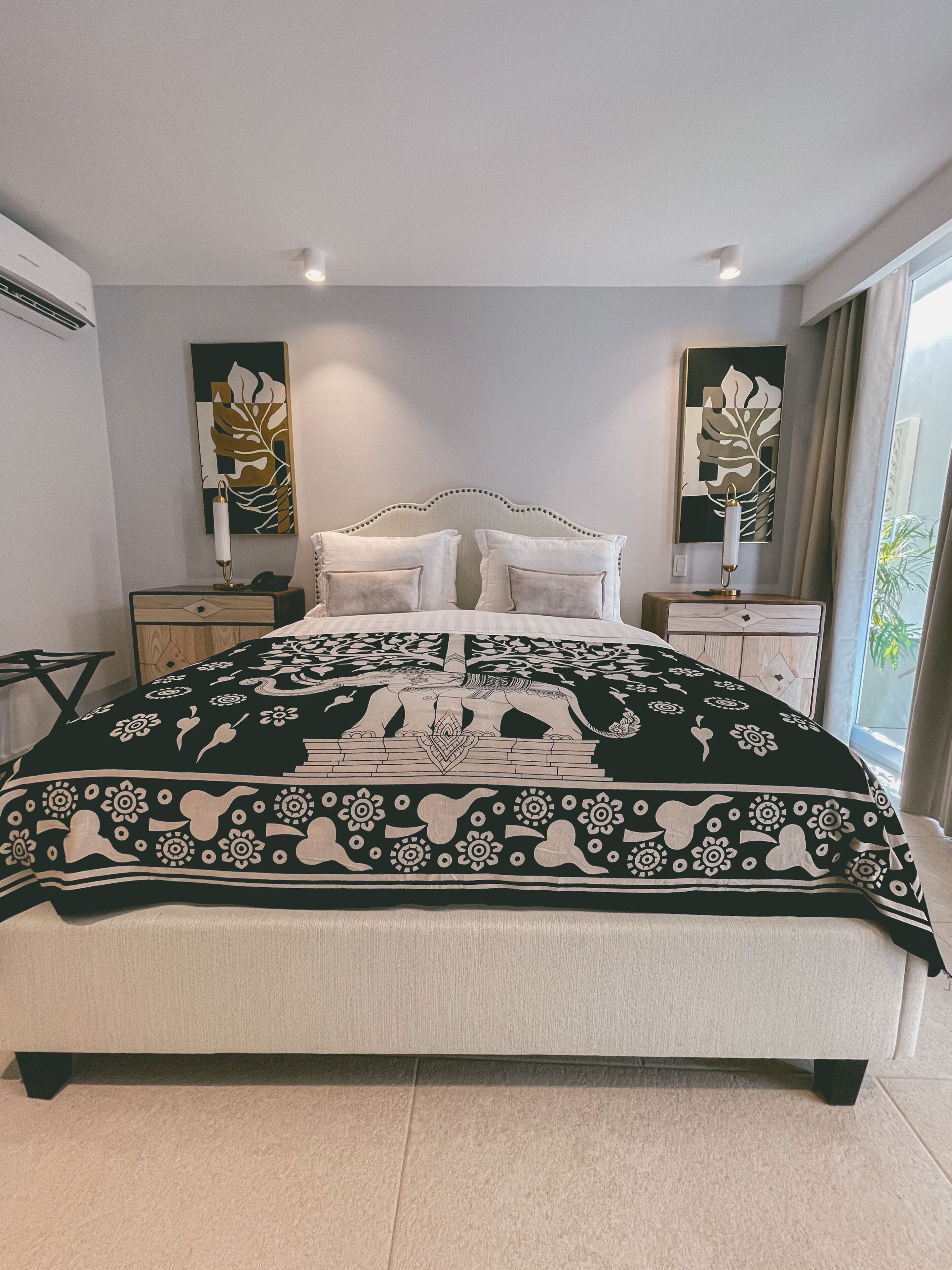 Quarto moderno com uma cama grande, duas mesas de cabeceira e obras de arte nas paredes.
