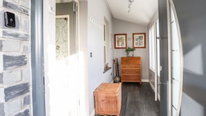 Un pasillo con pared de ladrillo, un banco de madera, un aparador y obras de arte enmarcadas en la pared.