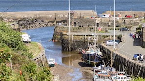 Un puerto costero con barcos amarrados, un muelle y una carretera con vehículos.