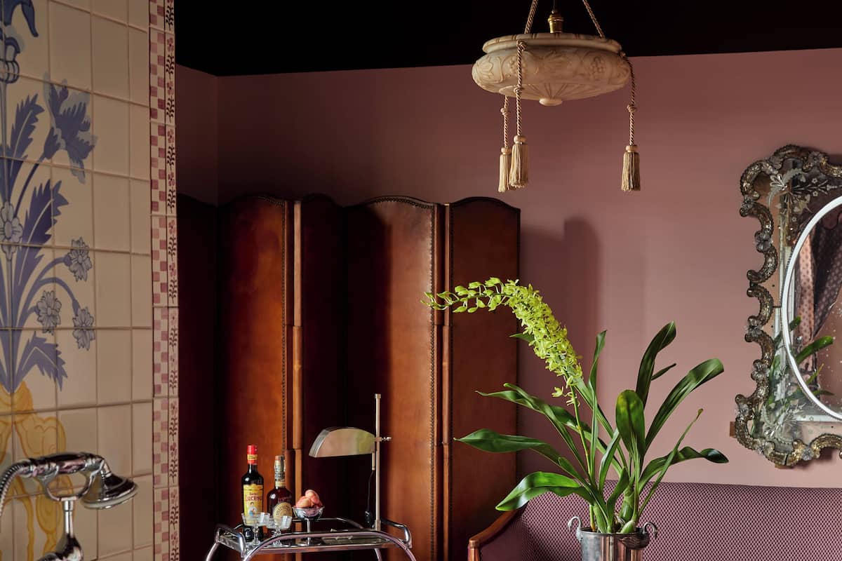 A bathroom with a bathtub, a sink with a vintage faucet, a mirror, a potted plant, and a seating area with a table and chairs.