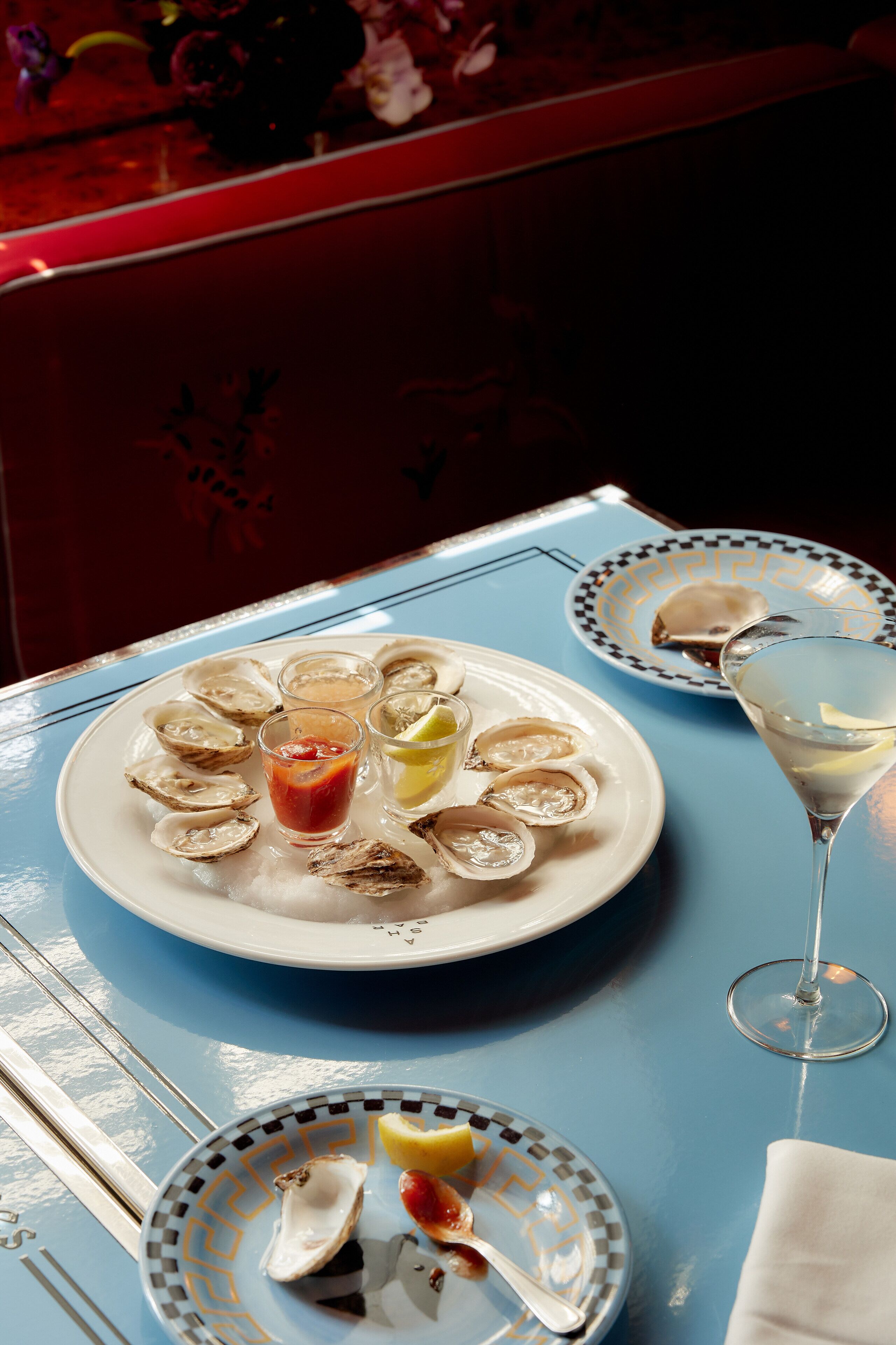 A table with plates of oysters, a martini glass, and a spoon.