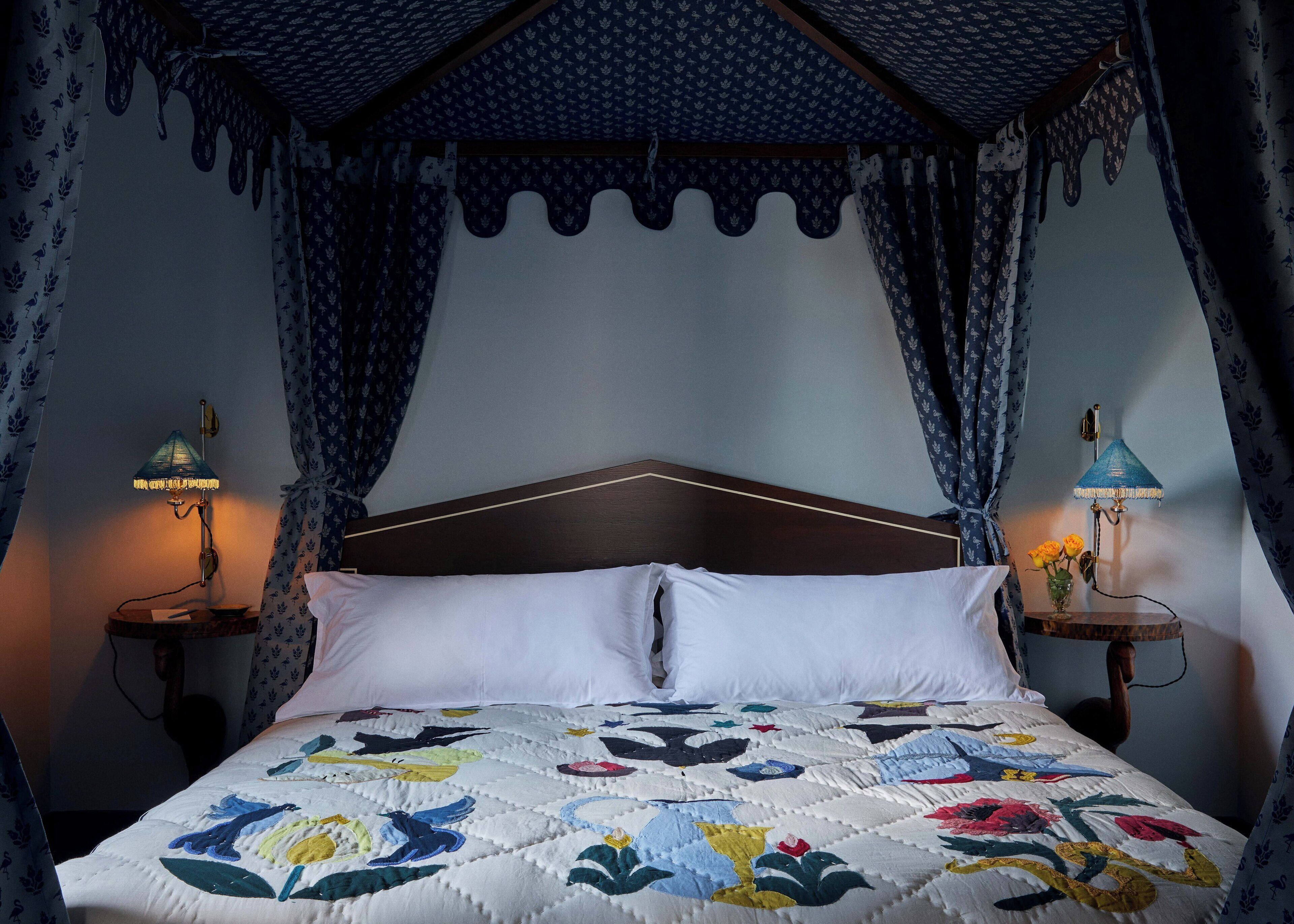 Ein Bett mit einer floralen Steppdecke, einem Holzkopfteil und zwei Nachttischlampen.