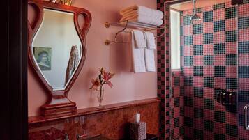 A bathroom with a vanity, a mirror, a towel rack, and a shower area with a checkered tile wall.
