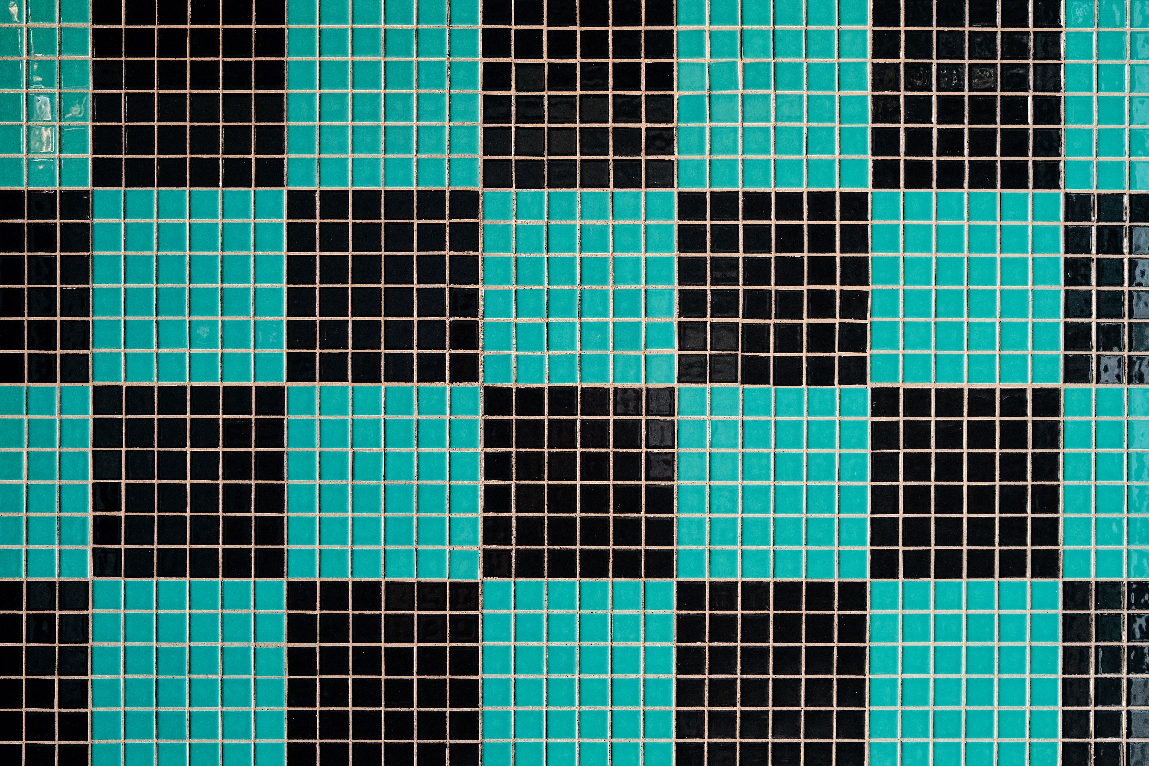 A tiled floor with a checkered pattern of black and teal tiles.
