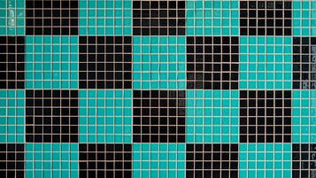 A tiled floor with a checkered pattern of black and teal tiles.