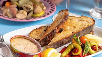 A table with a plate of food including bread, vegetables, and a can of spread.