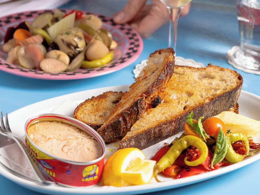 A table with a plate of food including bread, vegetables, and a can of spread.