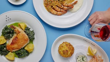 Three plates of food on a blue table with a glass of red wine.