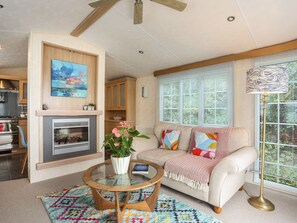 A living room with a fireplace, a sofa, a coffee table, and a large window with blinds.