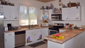A modern kitchen with white cabinets, a central island, and a window with blinds. - OCEAN FRONT Conch Shell-Green Turtle Cay with a dock- 15% SUMMER DISCOUNT! (Green Turtle Cay)