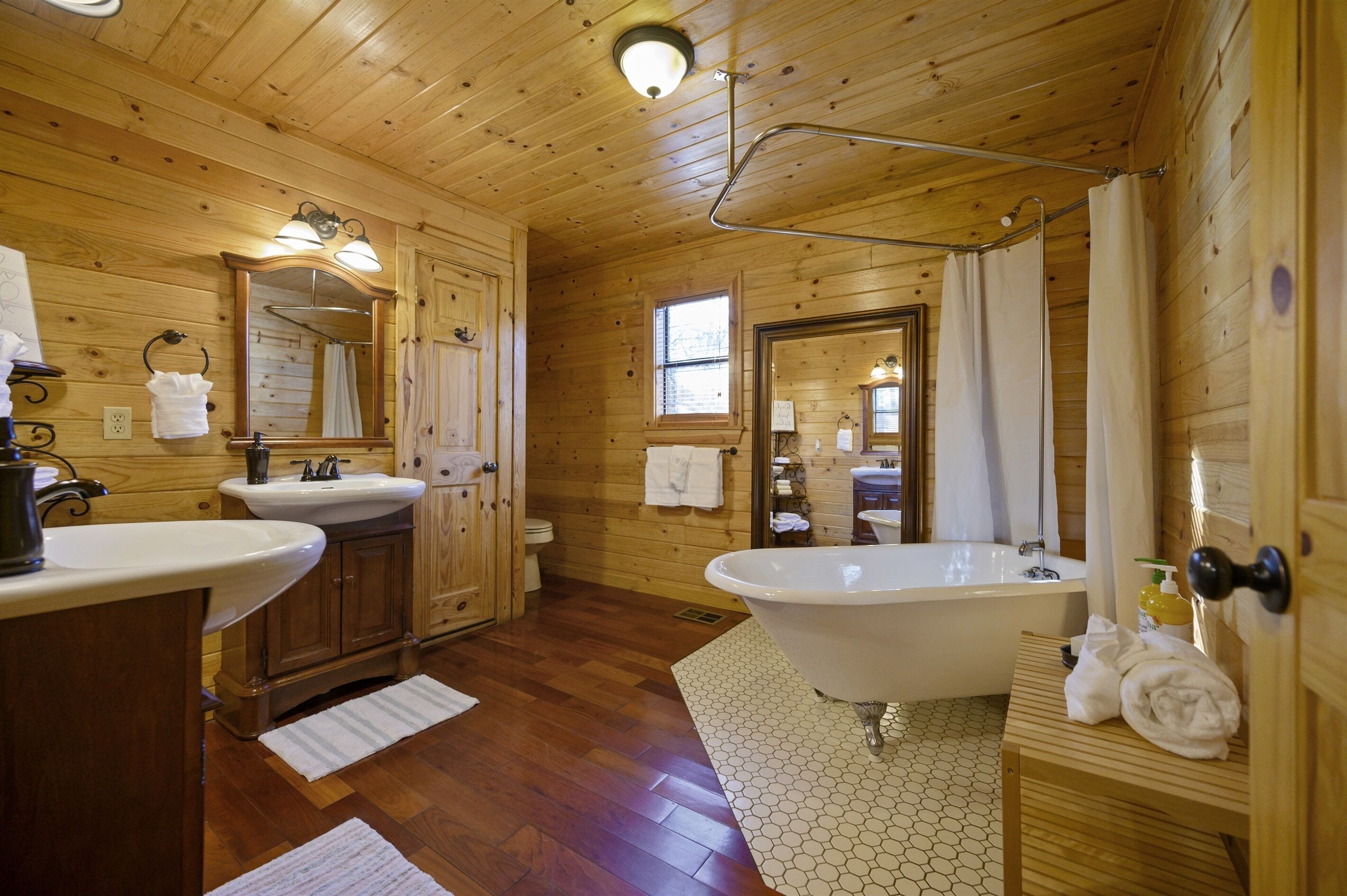 Un baño de cabaña de madera con lavamanos, tocador y una bañera independiente.
