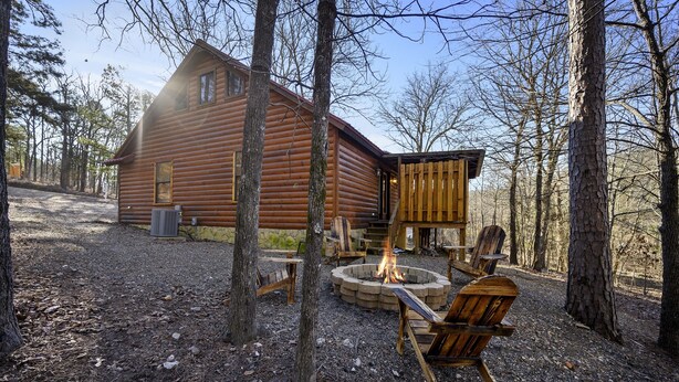 Une cabane en rondins avec un foyer et des sièges d’extérieur.