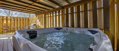 A hot tub with a wooden deck and a covered area.