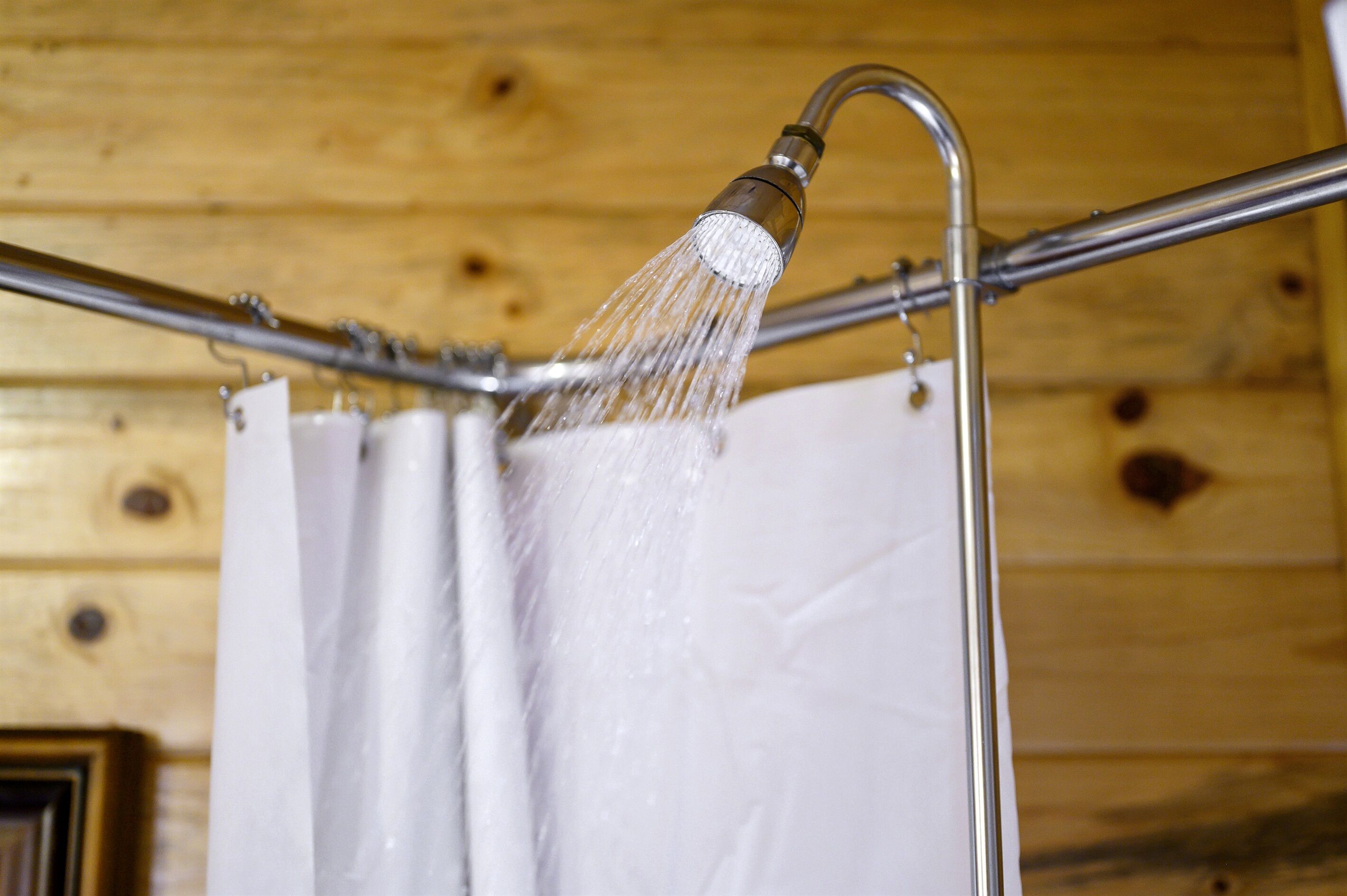Una ducha con agua corriendo desde un accesorio metálico en una habitación de madera.