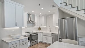 A modern kitchen with white cabinetry, stainless steel appliances, and a marble countertop. - Crystal Sands 312B. Completely Renovated Stunner, Free Beach Service, Pool. (Destin)