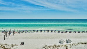A beach with rows of umbrellas and chairs, a sandy shore, and the ocean in the background. - Crystal Sands 312B. Completely Renovated Stunner, Free Beach Service, Pool. (Destin)