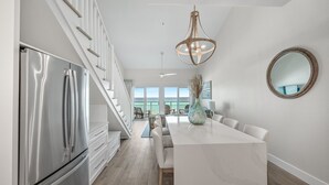 A modern kitchen with a stainless steel refrigerator, a marble island, and a large pendant light. - Crystal Sands 312B. Completely Renovated Stunner, Free Beach Service, Pool. (Destin)