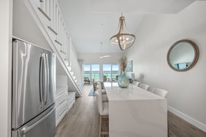 A modern kitchen with a stainless steel refrigerator, a marble island, and a large pendant light. - Crystal Sands 312B. Completely Renovated Stunner, Free Beach Service, Pool. (Destin)